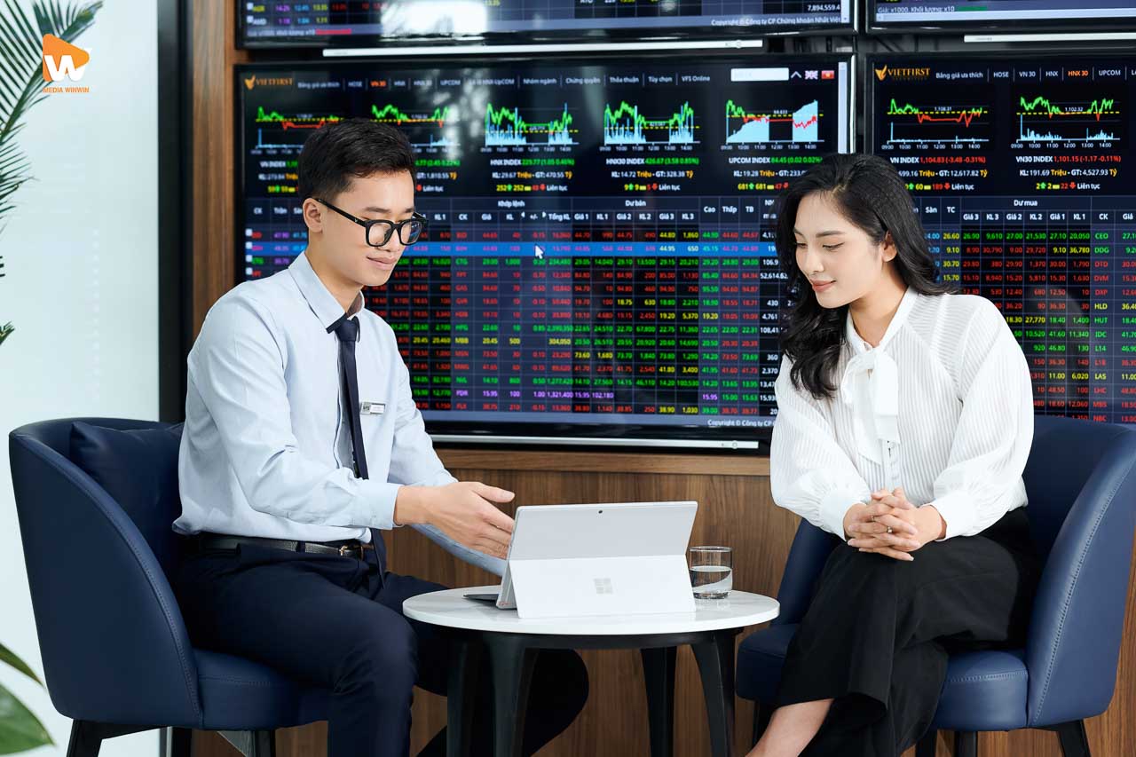 Chuyên viên VFS Securities tư vấn khách hàng trước tường màn hình bảng giá